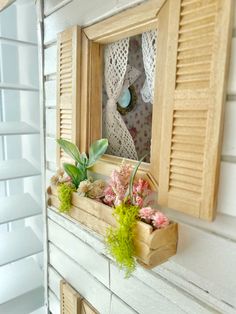 a window sill with flowers and plants in it on the side of a house