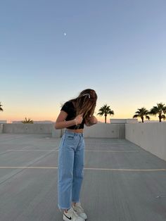 a woman is standing on her skateboard in the middle of an empty parking lot