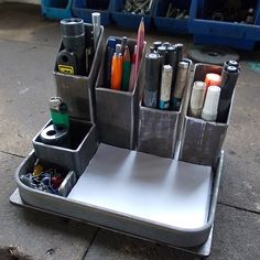 a metal holder with pens, pencils and other office supplies in it on the ground