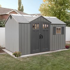 a gray storage shed sitting in the middle of a yard