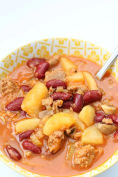 a close up of a bowl of soup with meat and fruit in it on a table