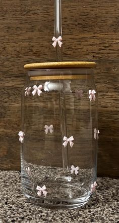 a glass jar with some pink flowers on it and a straw sticking out of the top