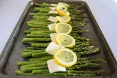 asparagus and lemon slices on a baking sheet