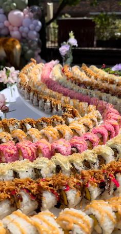 there are many different types of sushi on the table with flowers in the background