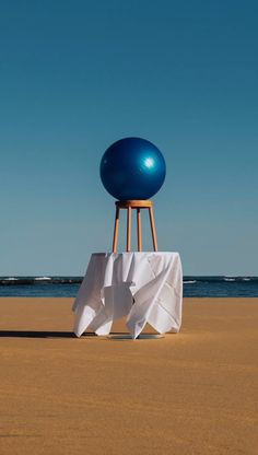 a chair sitting on top of a sandy beach next to the ocean under a blue sky