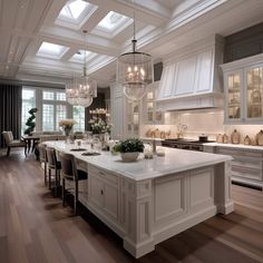 a large white kitchen with an island and chandelier hanging from the ceiling above it