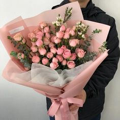 a man holding a bouquet of pink roses