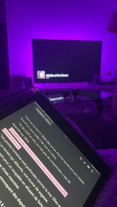 a laptop computer sitting on top of a bed in front of a purple lit room