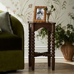 a green chair and table in front of a wallpapered room with flowers on it