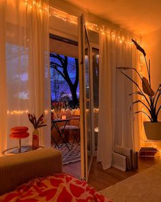 a living room filled with furniture next to a window covered in curtains and string lights