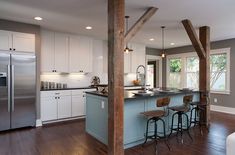 a kitchen with an island, refrigerator and two bar stools in it's center