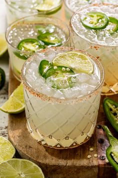 three margaritas with lime and jalapenos garnish on a cutting board