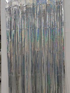 a curtain made out of silver foil on top of a white wall with other items in the background