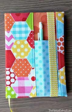 a small notebook covered in colorful fabric with a pen sticking out of the top one