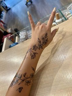 a woman's hand with a flower tattoo on her left arm and the middle finger