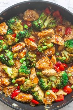 chicken and broccoli stir fry in a skillet with sesame seeds on the side