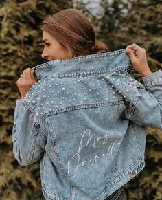 a woman wearing a jean jacket with pearls on it