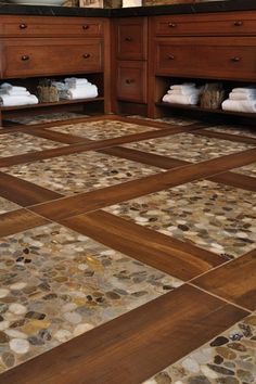 a large bathroom with brown cabinets and white towels on the counter tops, along with marble tile flooring