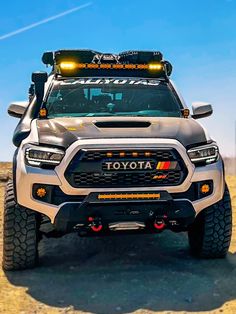 the front end of a silver truck with lights on