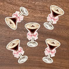 four stickers with chocolate and pink bows on them sitting next to each other in front of a wooden surface