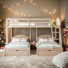 two bunk beds in a bedroom with christmas lights on the wall and tree behind them