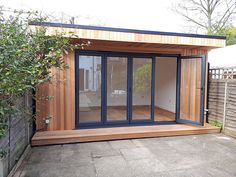 an outdoor room with sliding glass doors on the outside and wooden decking around it