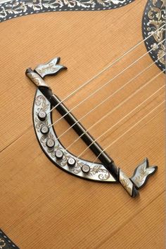 a close up of an instrument with metal decorations on the top and bottom, sitting on a wooden surface