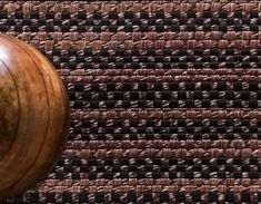 a wooden ball sitting on top of a brown and black rug