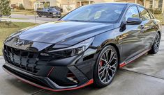 a black sports car parked in front of a house