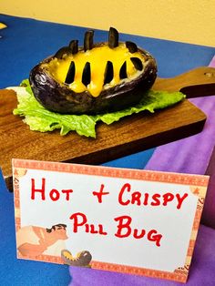 a hot and crispy phil bug is on a wooden board next to a sign that says hot and crispy phil bug