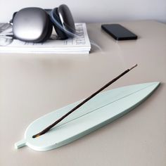 a surfboard with two sticks sticking out of it sitting on a table next to headphones