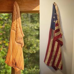 an american flag hanging on the wall next to a wooden cross with two flags in it