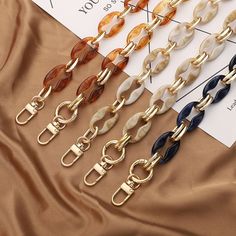 six different colors of chain with metal clasps on top of a sheet of fabric