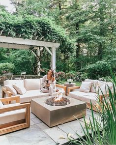 a woman sitting on top of a couch next to a fire pit in a garden