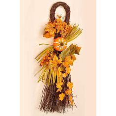 an orange and yellow fall wreath hanging on a wall with dried flowers, leaves and pumpkins