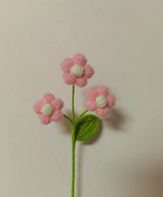 a crocheted pink flower with green leaves