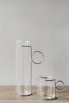 two clear glass vases sitting on top of a wooden table next to each other