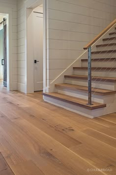 an empty living room with wood flooring and white walls, stairs leading up to the second floor