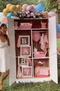 a woman standing in front of a baby's box with balloons and decorations on it