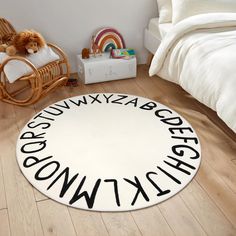 a white rug with black letters on the floor and a teddy bear sitting in a rocking chair