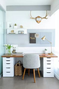 a desk with some drawers and a chair next to it in front of a wall mounted deer head