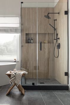 a walk in shower sitting next to a wooden bench on top of a tiled floor