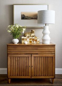 a wooden cabinet with vases and flowers on it in front of a framed photograph