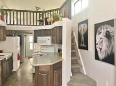 an open kitchen and living room with stairs leading up to the second floor, along with pictures on the wall