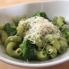 a white bowl filled with pasta and broccoli covered in parmesan cheese