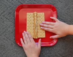 two hands reaching for crackers on a red plate