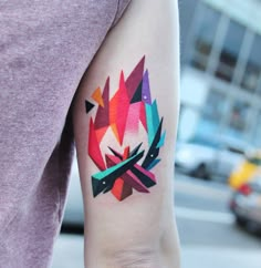 a person with a colorful tattoo on their left arm and the other arm behind her