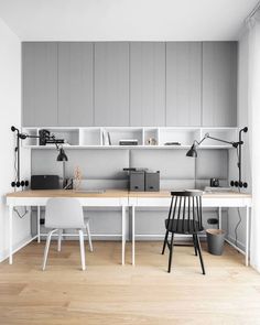 an office with two desks and shelves on the wall above them, along with chairs