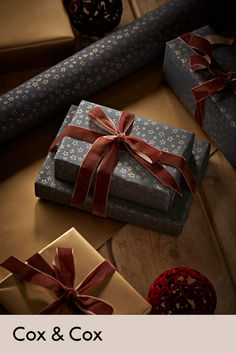 two wrapped presents sitting next to each other on top of a wooden table with red ribbon