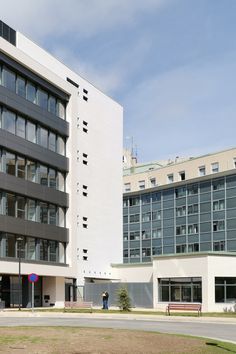 the building is white and has many windows on each side, along with a bench in front of it